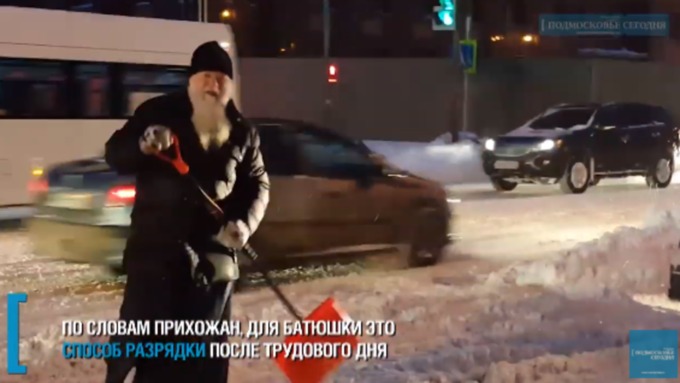 Священнику за 70 лет, но он по-молодецки лопатой раскидывает снег с дороги / Фото: кадр из видео