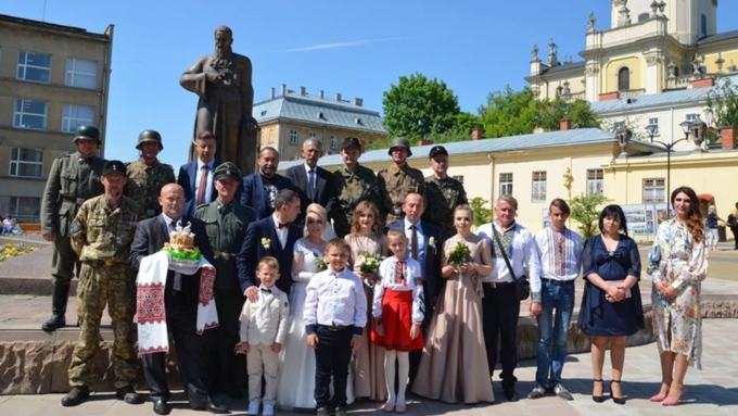 Молодожены вместе с гостями сфотографированы на фоне памятника митрополиту / Фото: facebook.com/eduard.dolinsky
